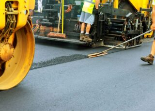 Road workers laying down fresh blacktop pavement