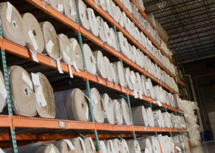 A vast warehouse containing rolls of industrial carpet