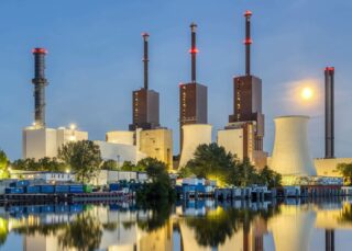 An industrial power plant reflected in water at dusk