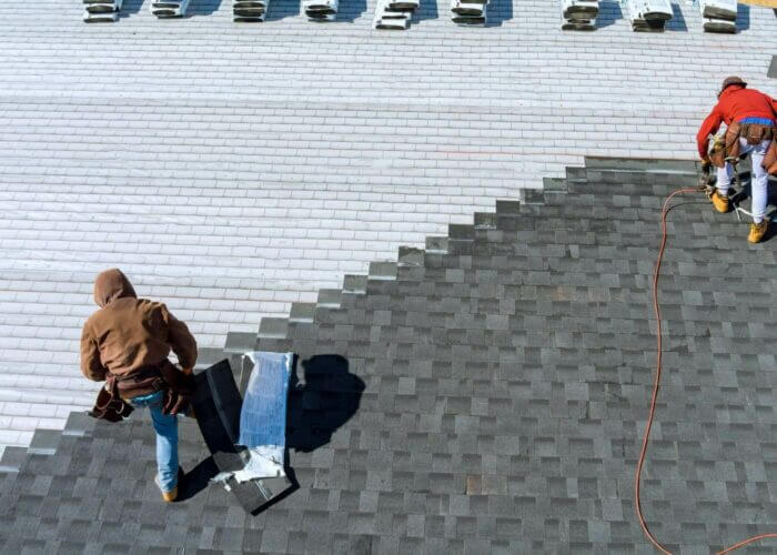 Workers installing asphalt roof shingles