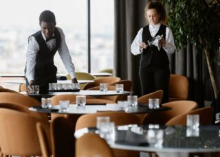 Restaurant staff preparing for opening with two servers setting tables