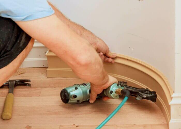 Carpenter using nail gun to Moulding framing trim