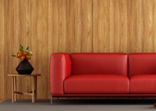 Red couch in front of a wood veneer wall