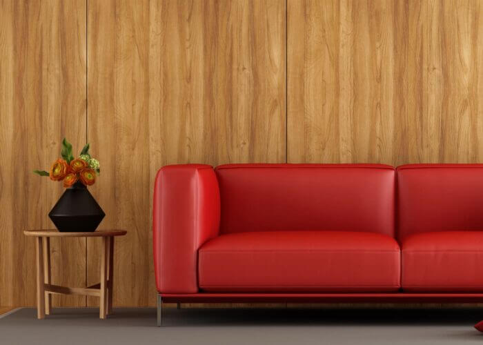 Red couch in front of a wood veneer wall