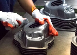 Gloved worker polishing stamped metal automotive parts