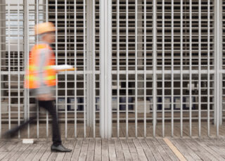 Worker walking in front of a commercial metal fence