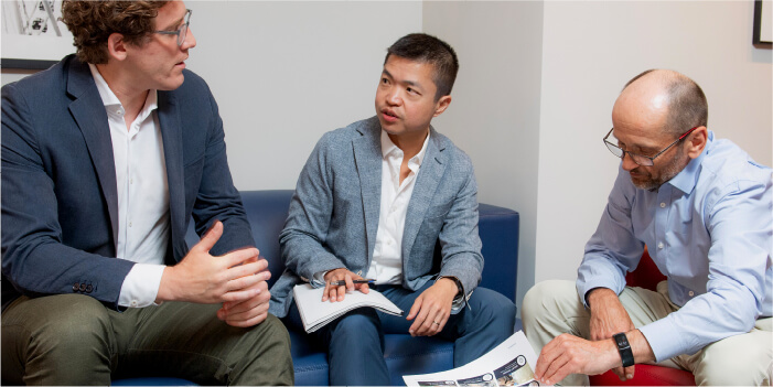 Three executives review a research document in a conference room