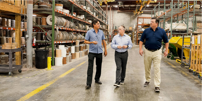 three executives walking the warehouse floor